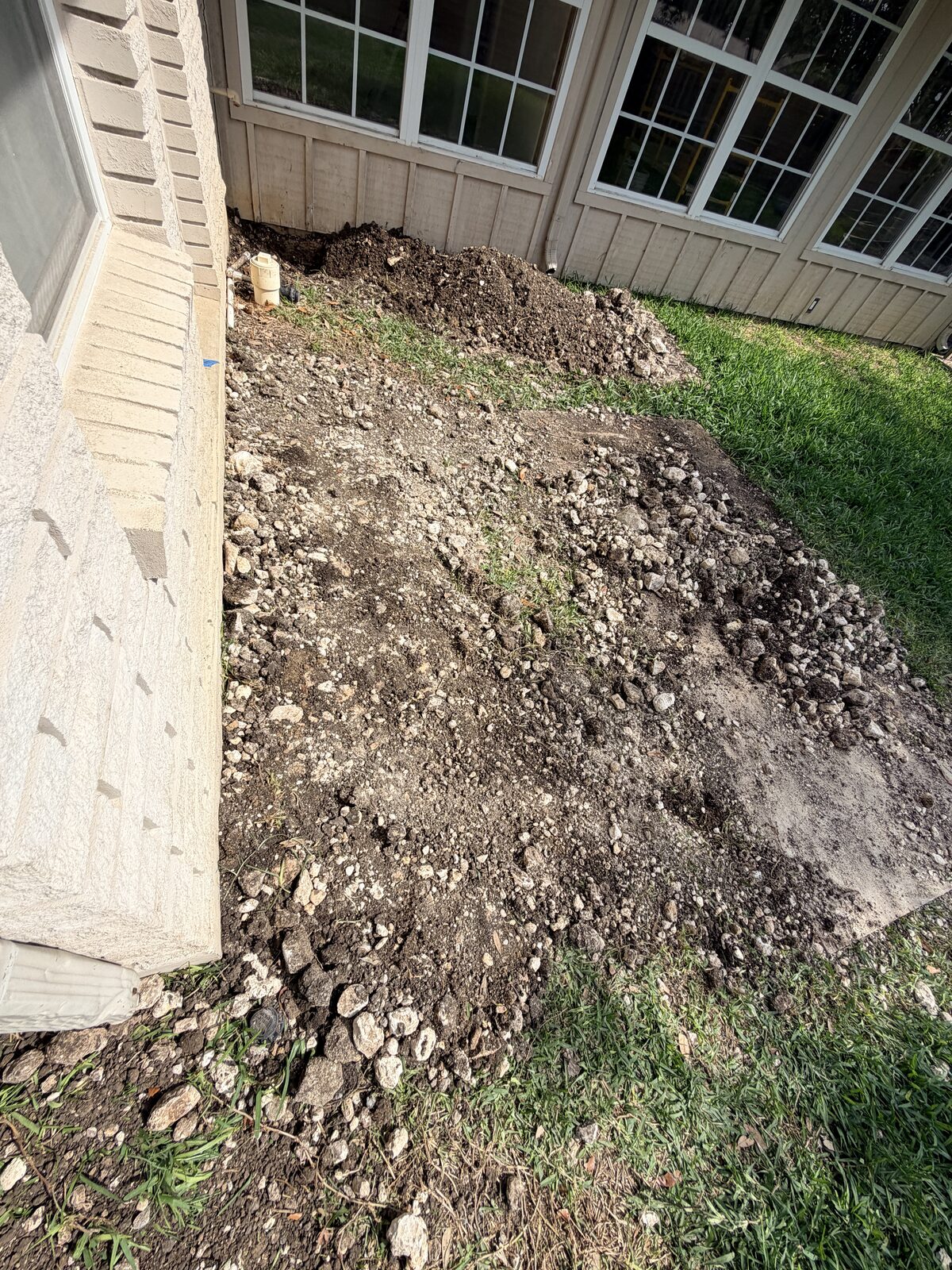 A backfilled excavation under bay windows — the dig closed clean.