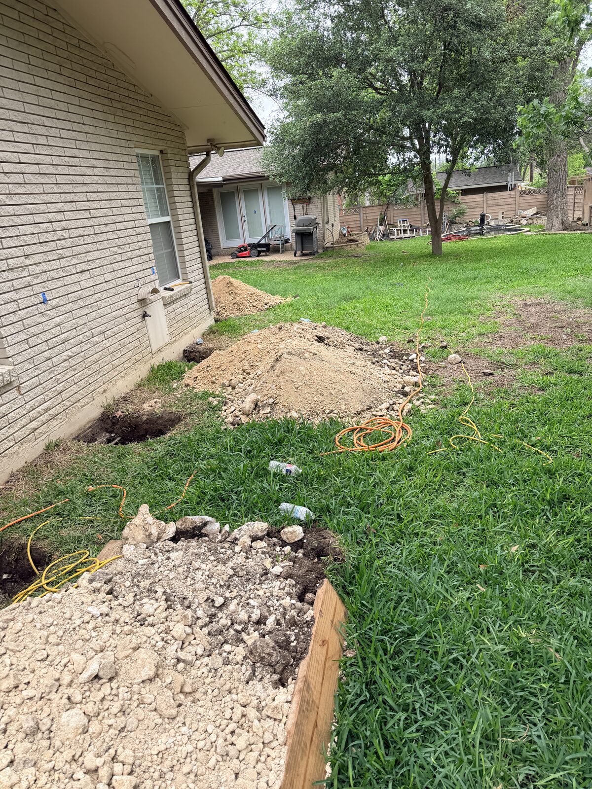 Backyard foundation repair jobsite with spoil piles from pier excavation