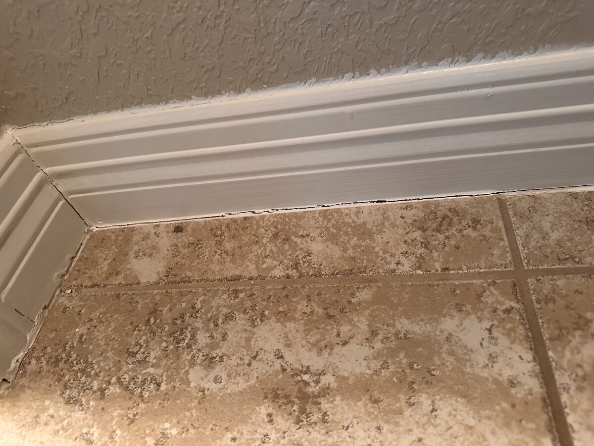 Baseboard pulling away from a travertine tile floor as the slab settles beneath the home