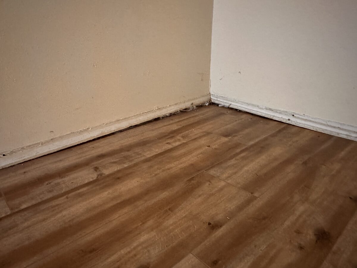 Room corner where the baseboard has separated from a sloping floor due to foundation settlement