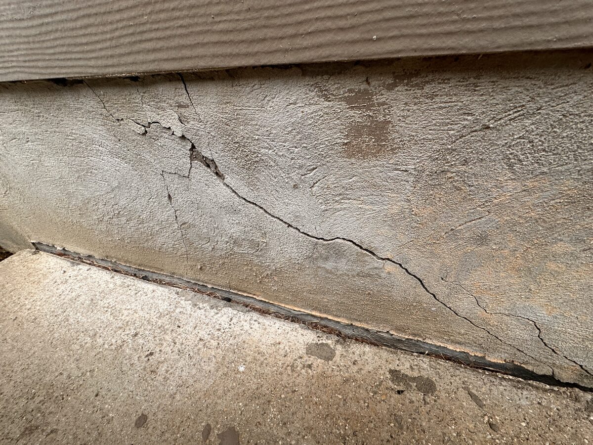 Close-up of a branching crack in a home's concrete slab edge, documented during a foundation inspection