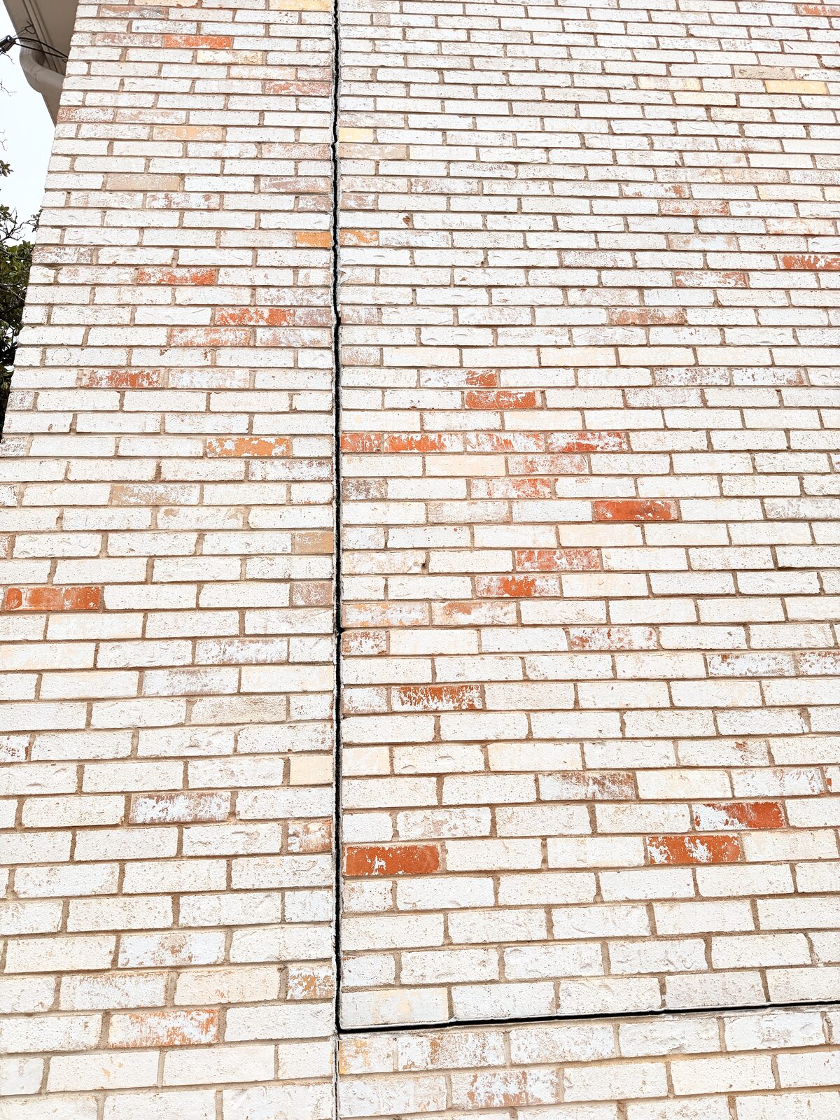 Centered vertical crack-repair line with patched bricks in a wall restored after foundation work