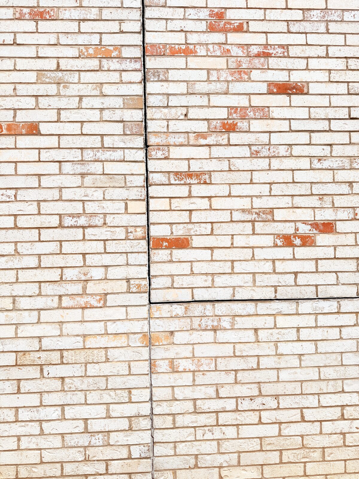 Repointed vertical crack and brick patches on the right side of a repaired masonry wall