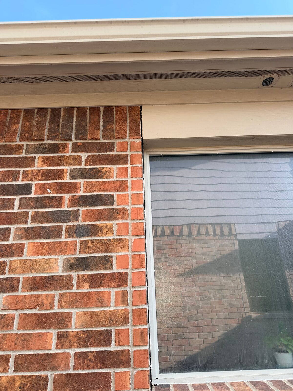 Brick veneer pulled away from a window frame, leaving a gap along the jamb