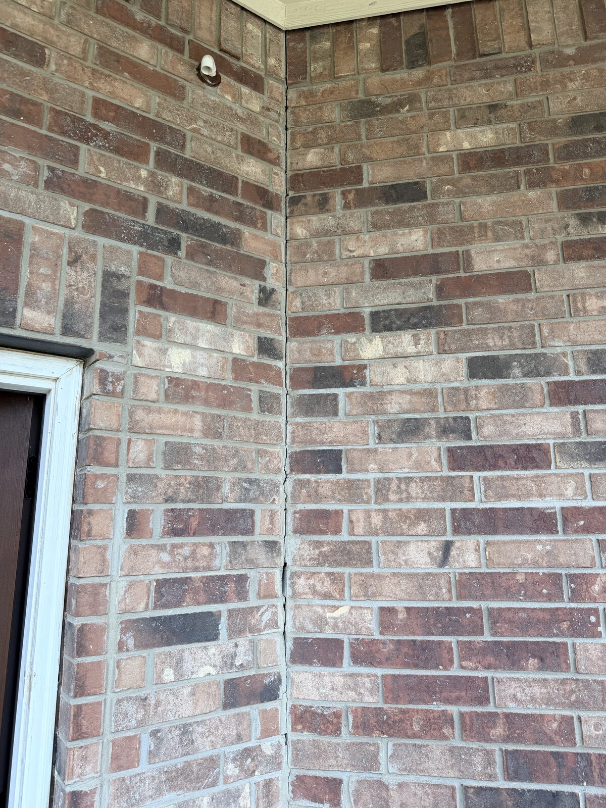 Vertical mortar separation at a brick veneer corner near a front door, an early sign of foundation settlement