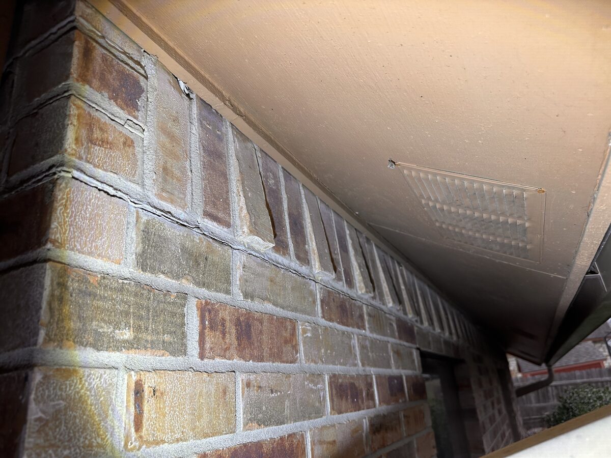 Widening gap between the top course of brick veneer and the porch soffit, a sign the foundation has settled