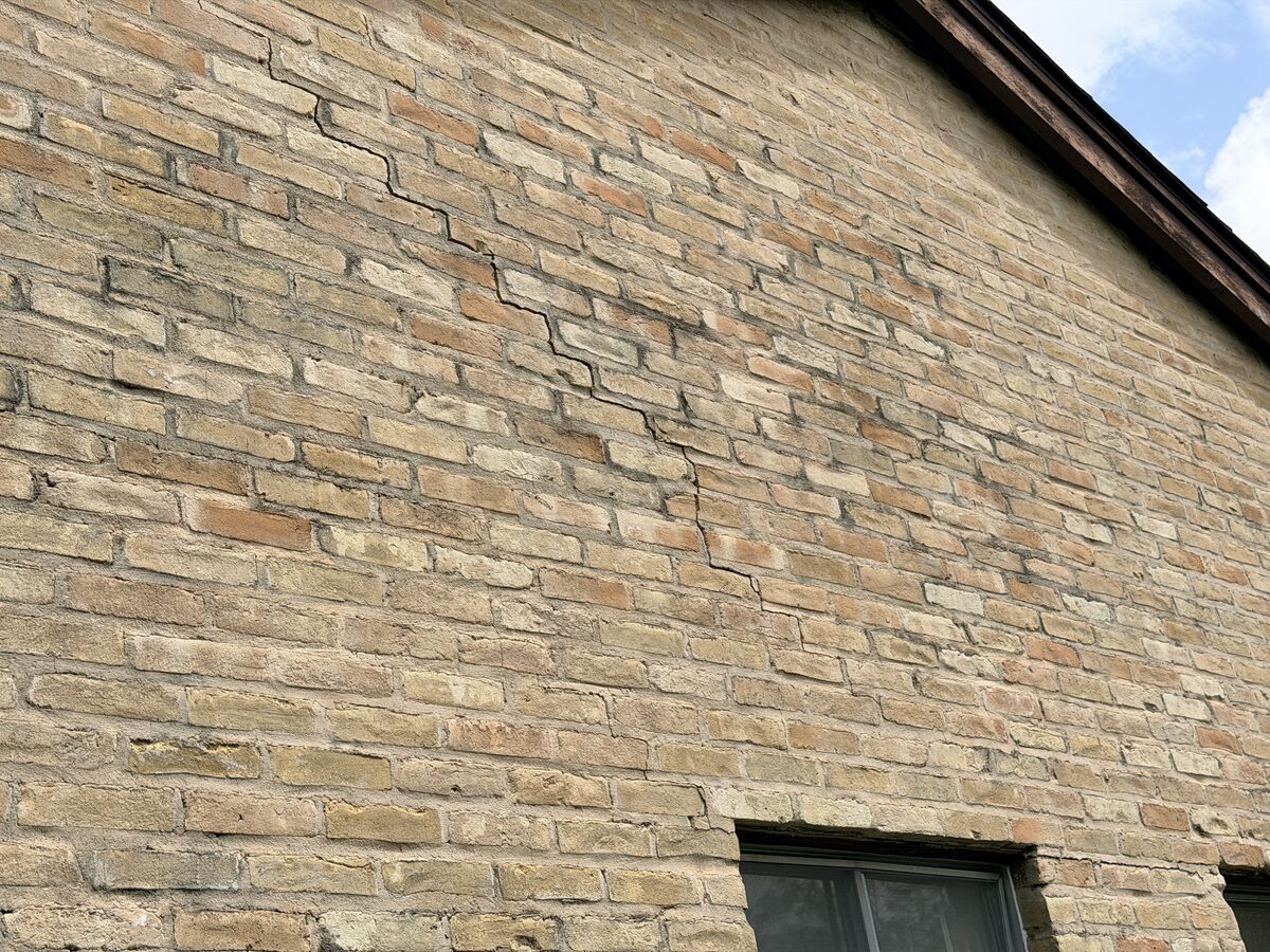 Surveying a brick wall, window, and roofline for foundation movement