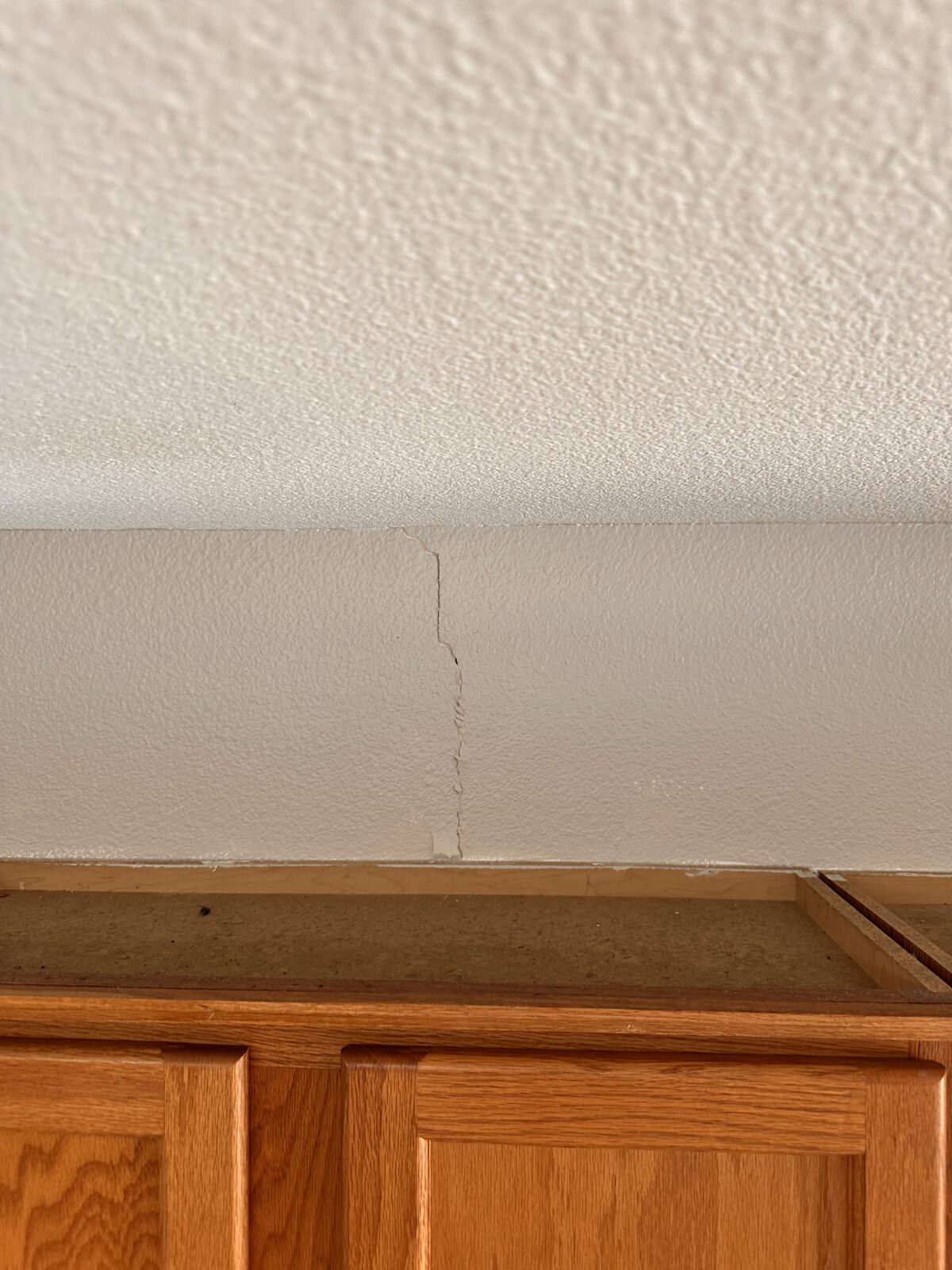 Wall-to-ceiling crack above kitchen cabinets caused by foundation settlement
