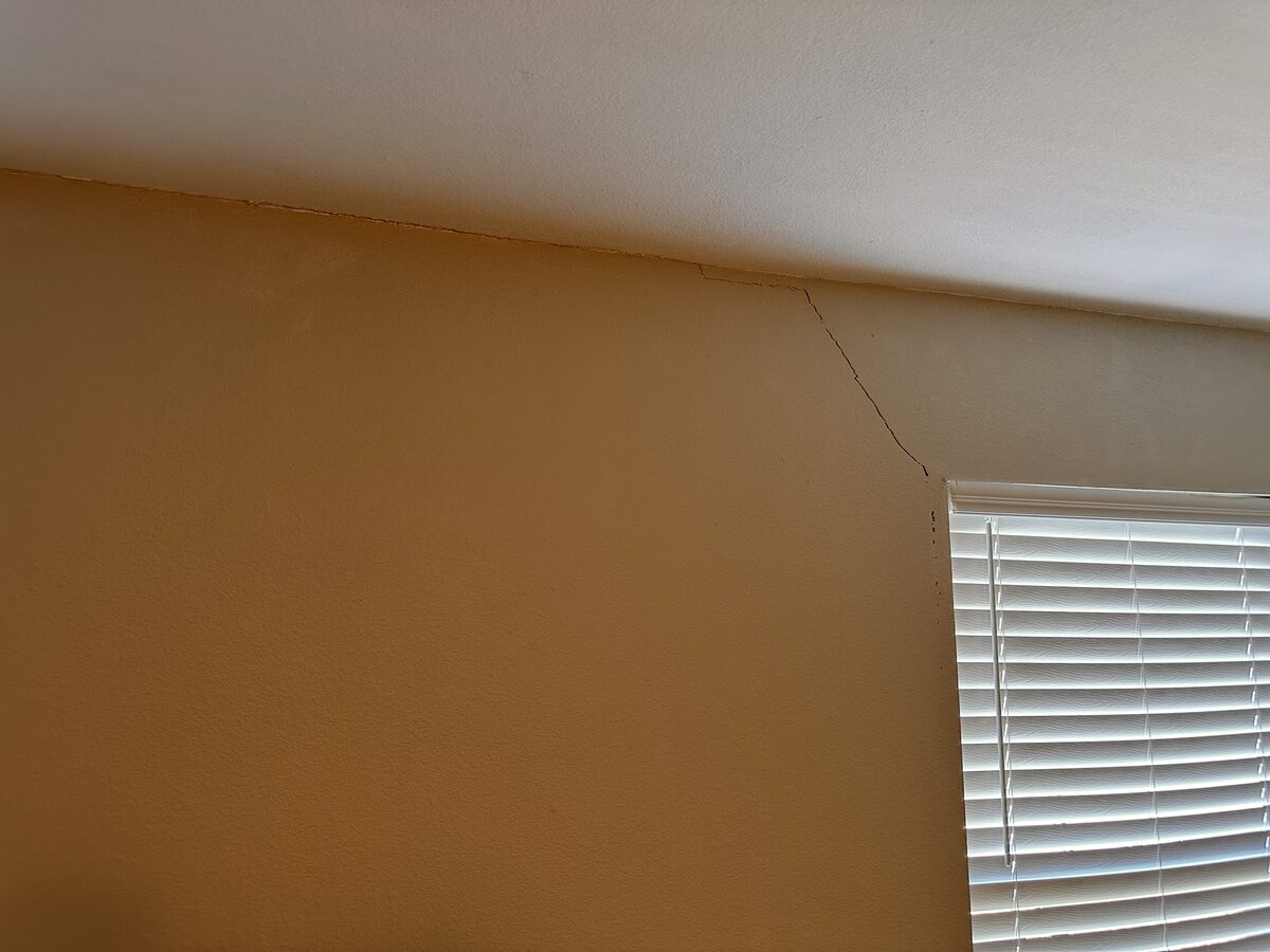 Diagonal crack running from the ceiling line to a window corner, a classic sign of foundation settlement