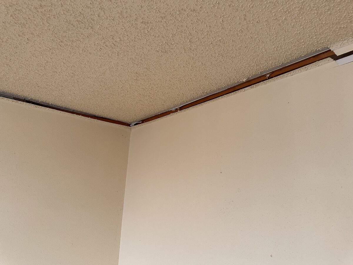 Gap at the ceiling trim corner where walls have pulled apart from foundation settlement