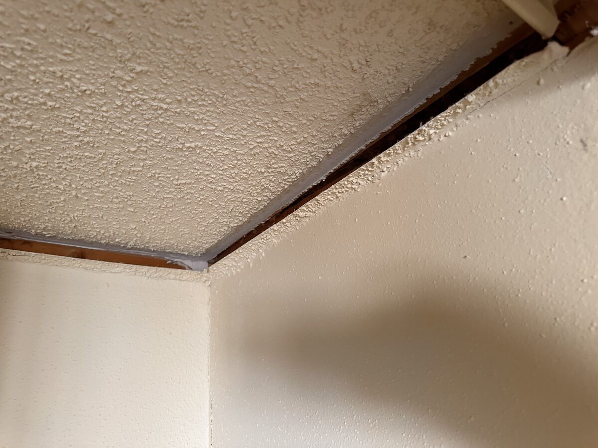 Close-up of the wall separating from the ceiling line, documented during a foundation inspection