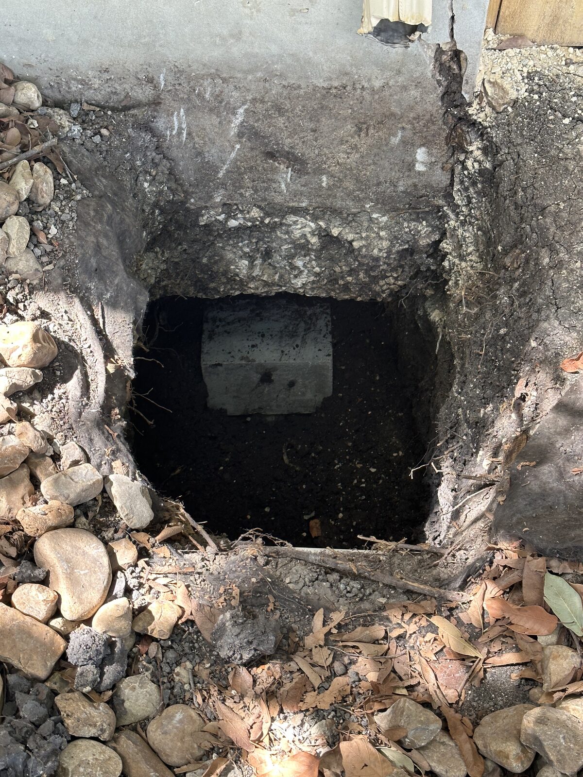 Concrete pier cap set in an excavated pit beneath a home's grade beam during foundation underpinning
