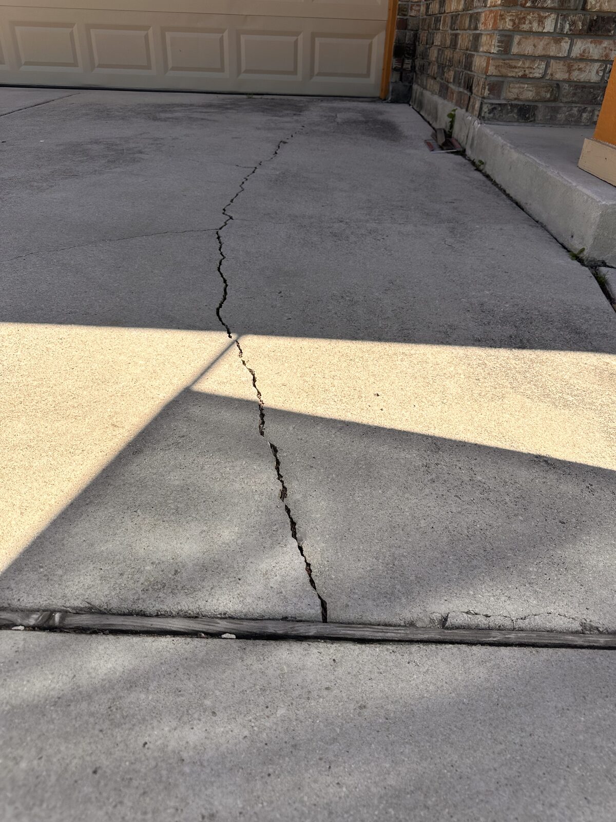 Crack crossing a backyard concrete patio slab, photographed during a foundation evaluation