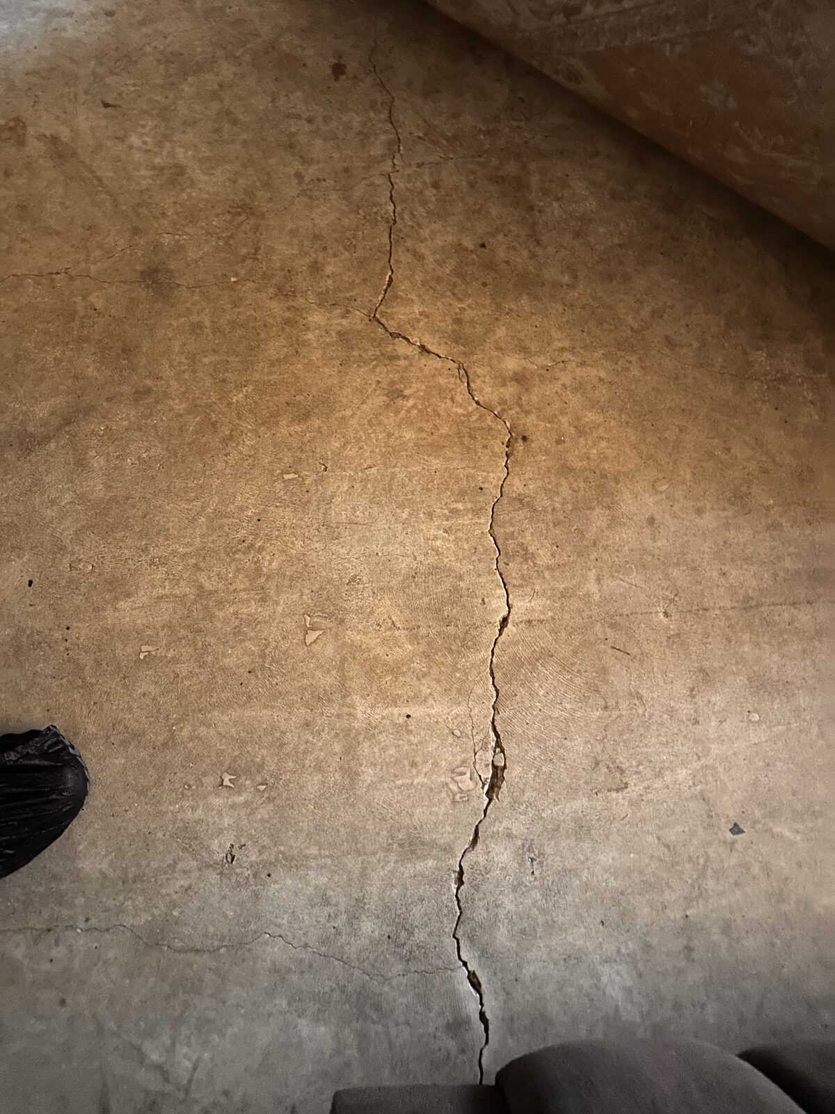 Long crack running across a bare interior concrete slab floor, evaluated during a foundation repair assessment