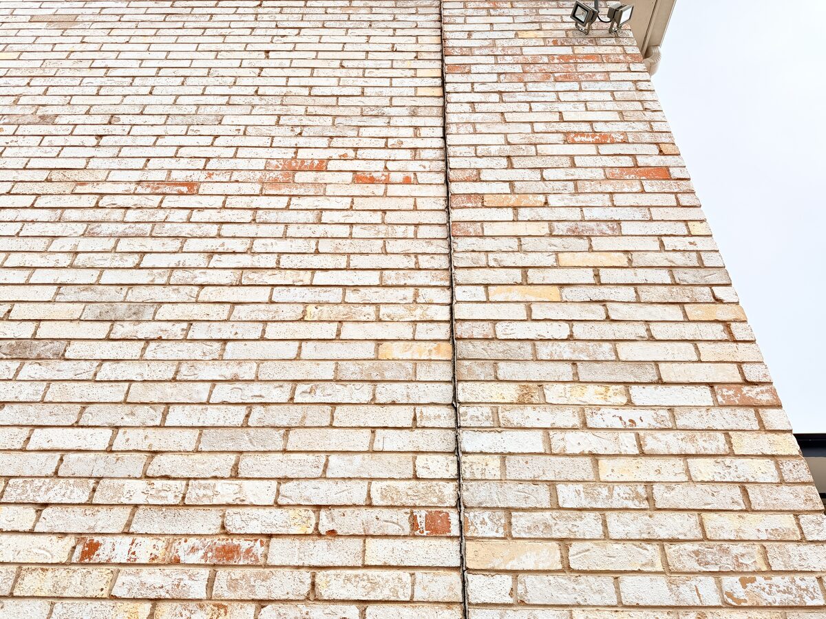Repointed crack line running up a brick wall to the soffit, repaired after foundation movement