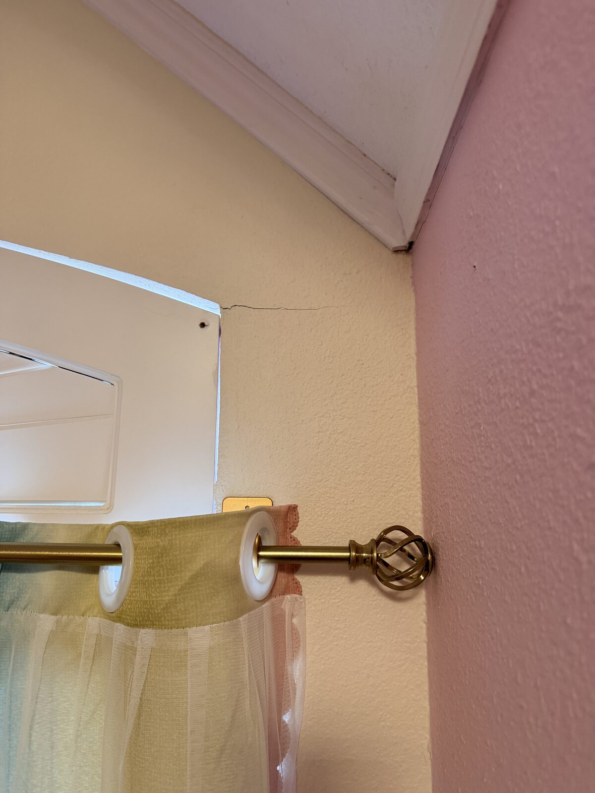 Crack running from a window header up toward a vaulted ceiling in a settling home