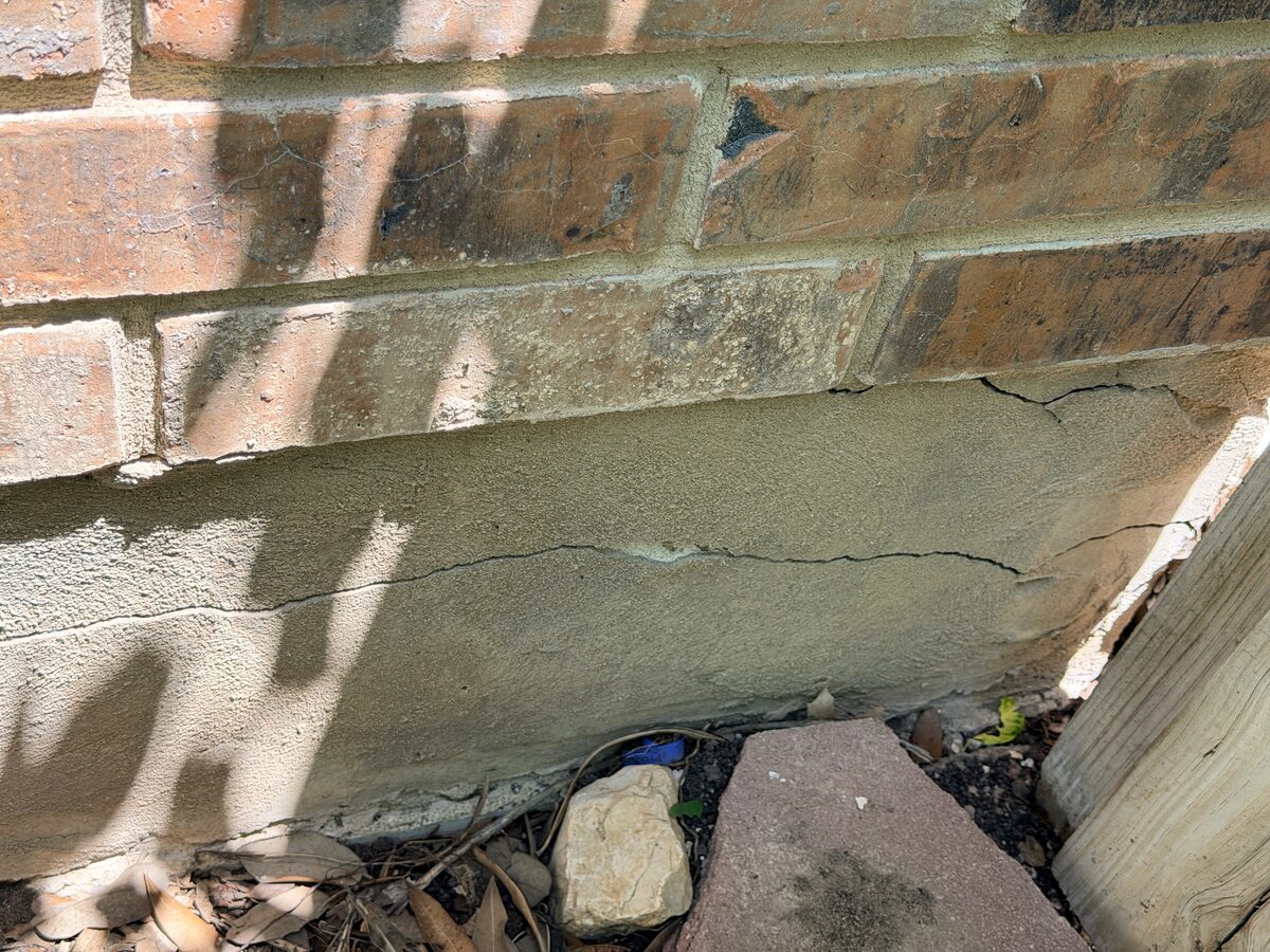 Long crack in the mortar cap along the top of a brick wall
