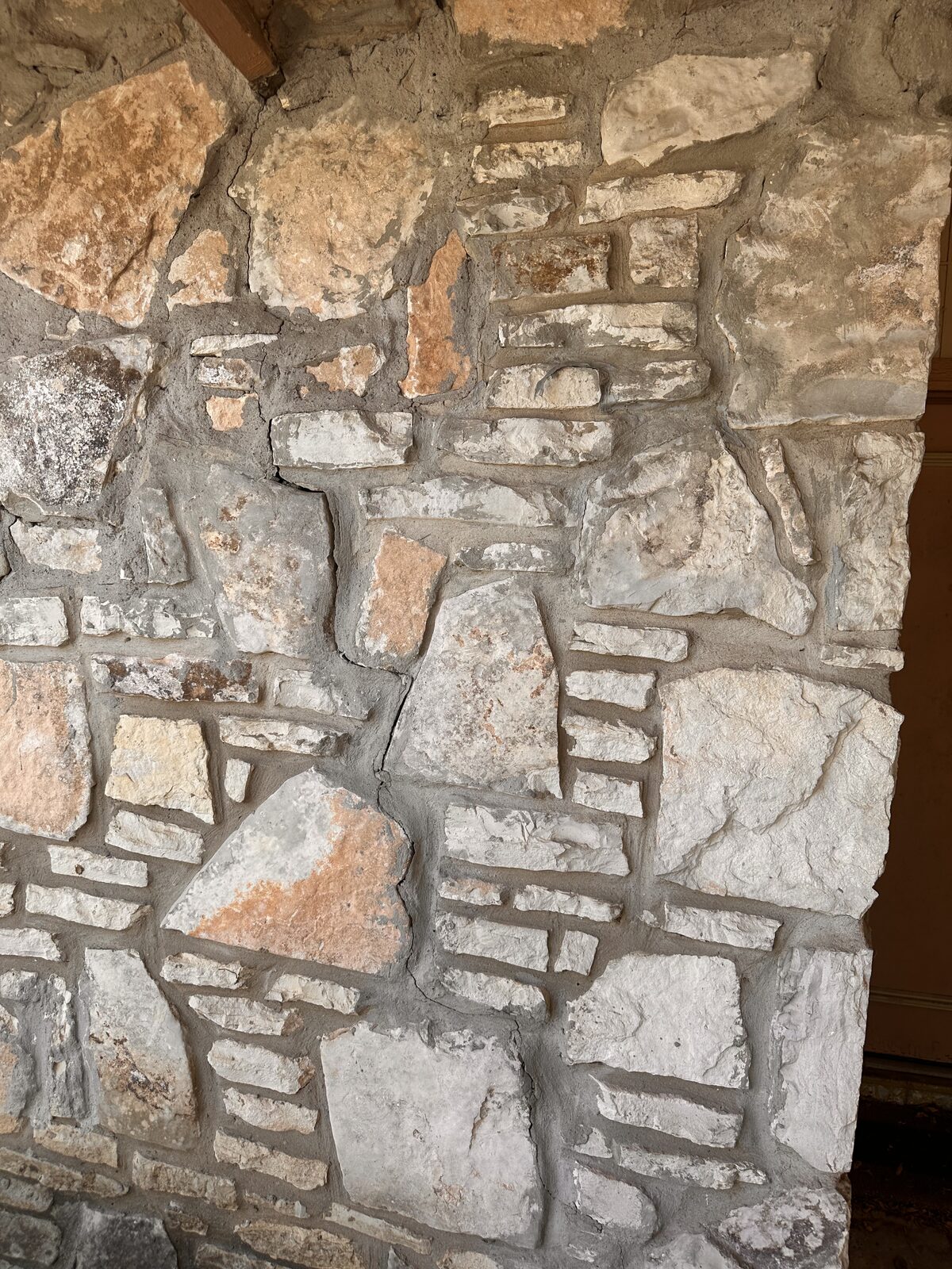 Close-up of cracked mortar joints in limestone veneer caused by foundation movement