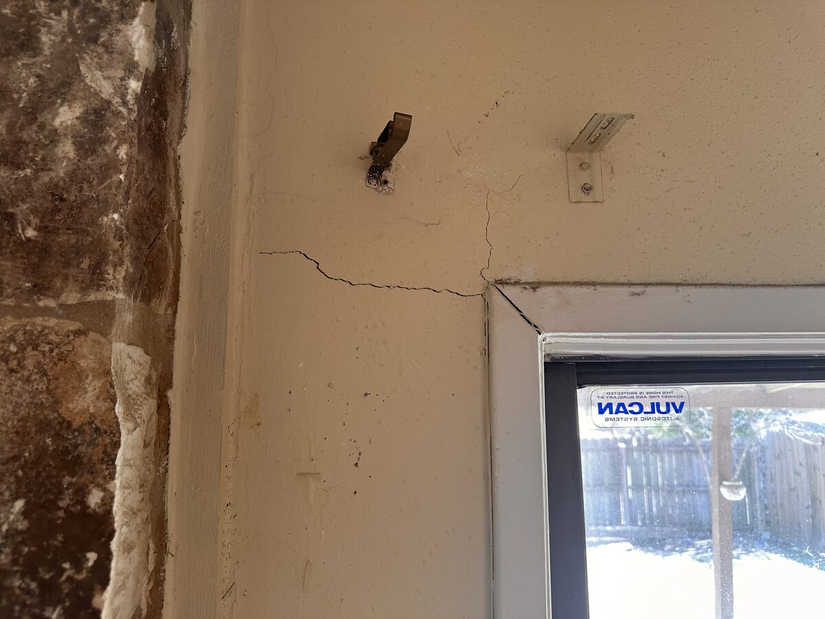 Cracked plaster and separation around a window frame in an older home with foundation issues