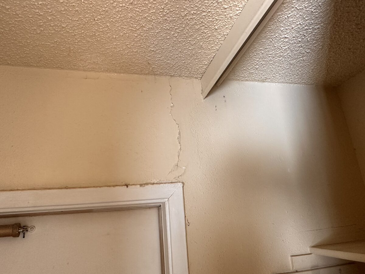Cracked plaster at a ceiling corner above a closet door in a home with foundation settlement