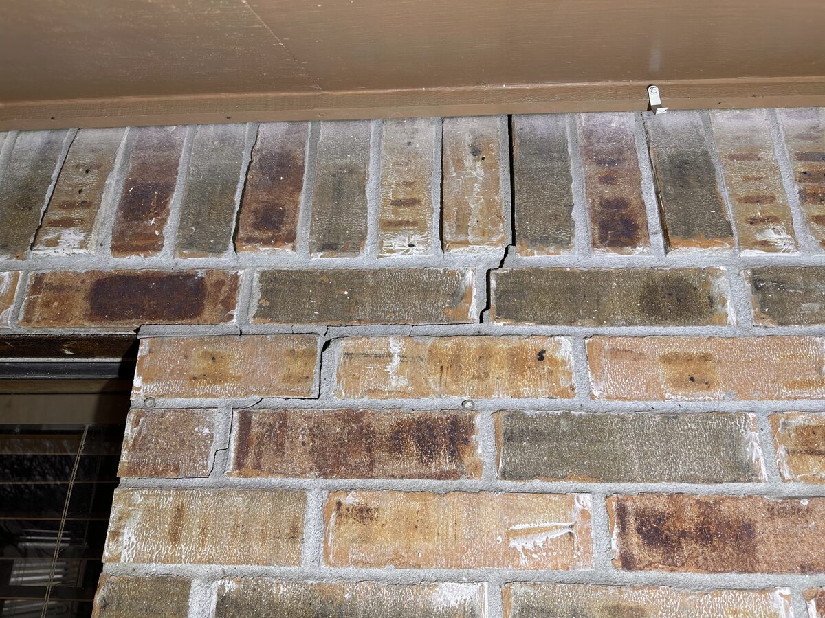 Crack and shifted soldier-course bricks above a window lintel caused by foundation movement
