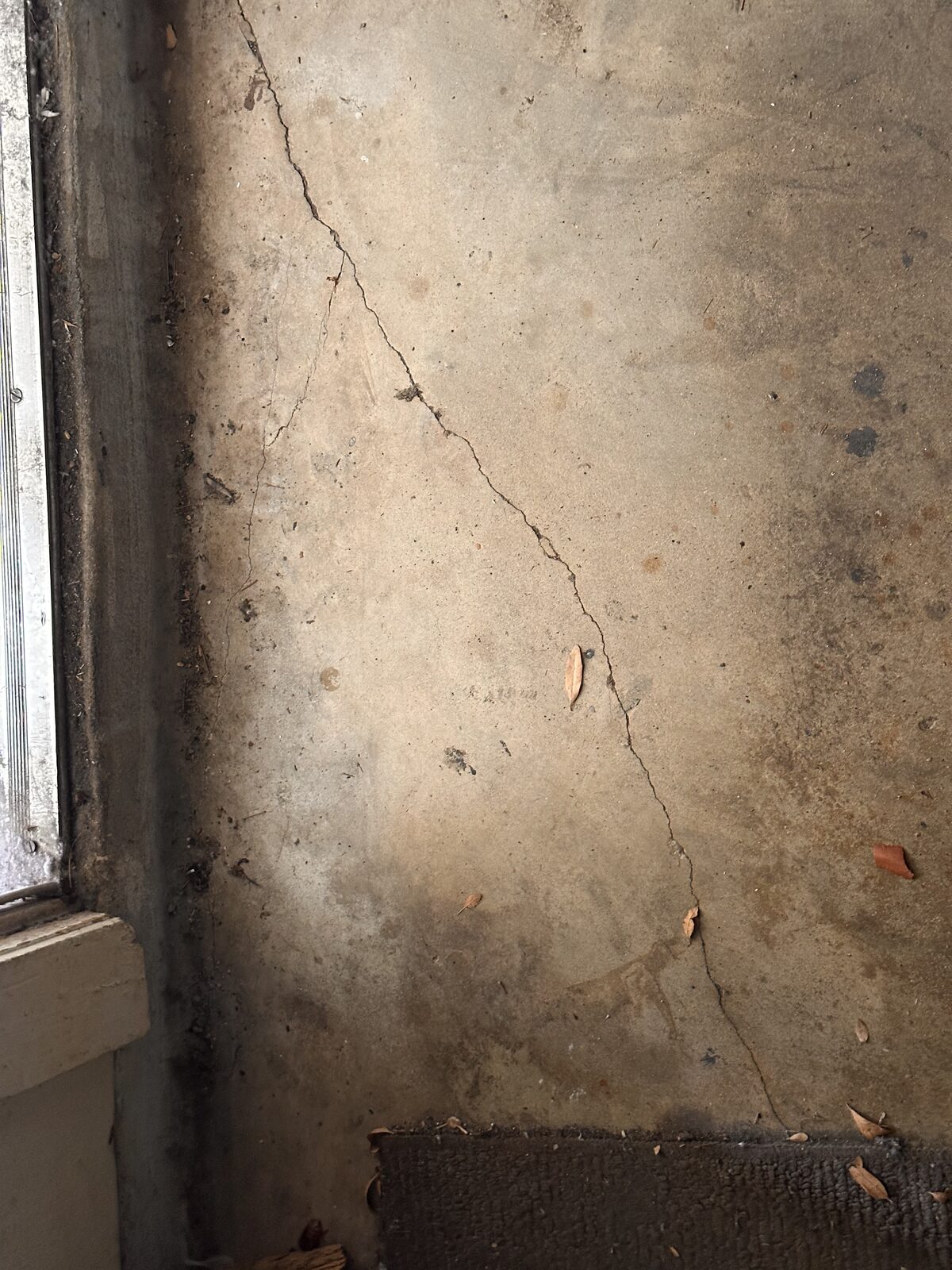 Cracked and moisture-stained plaster beside a window where foundation movement let water intrude