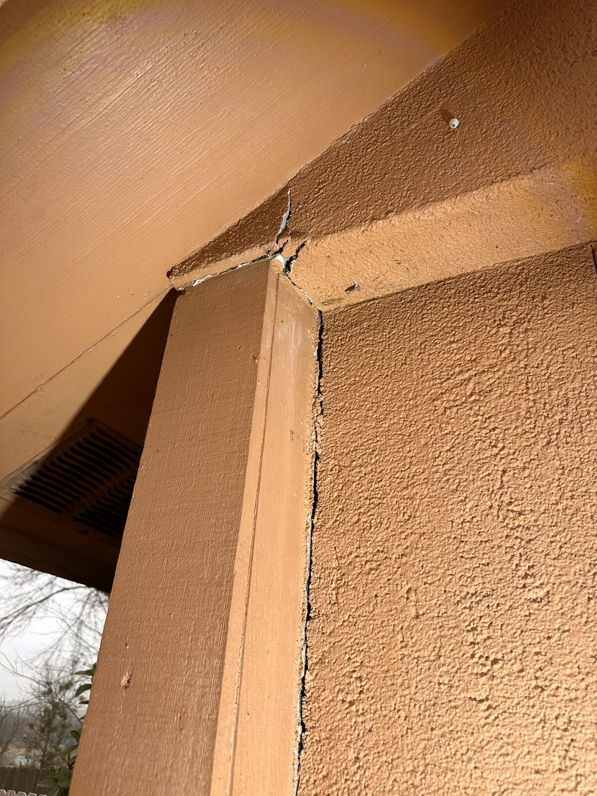 Cracked, separating trim where a porch column meets the header, often caused by foundation movement