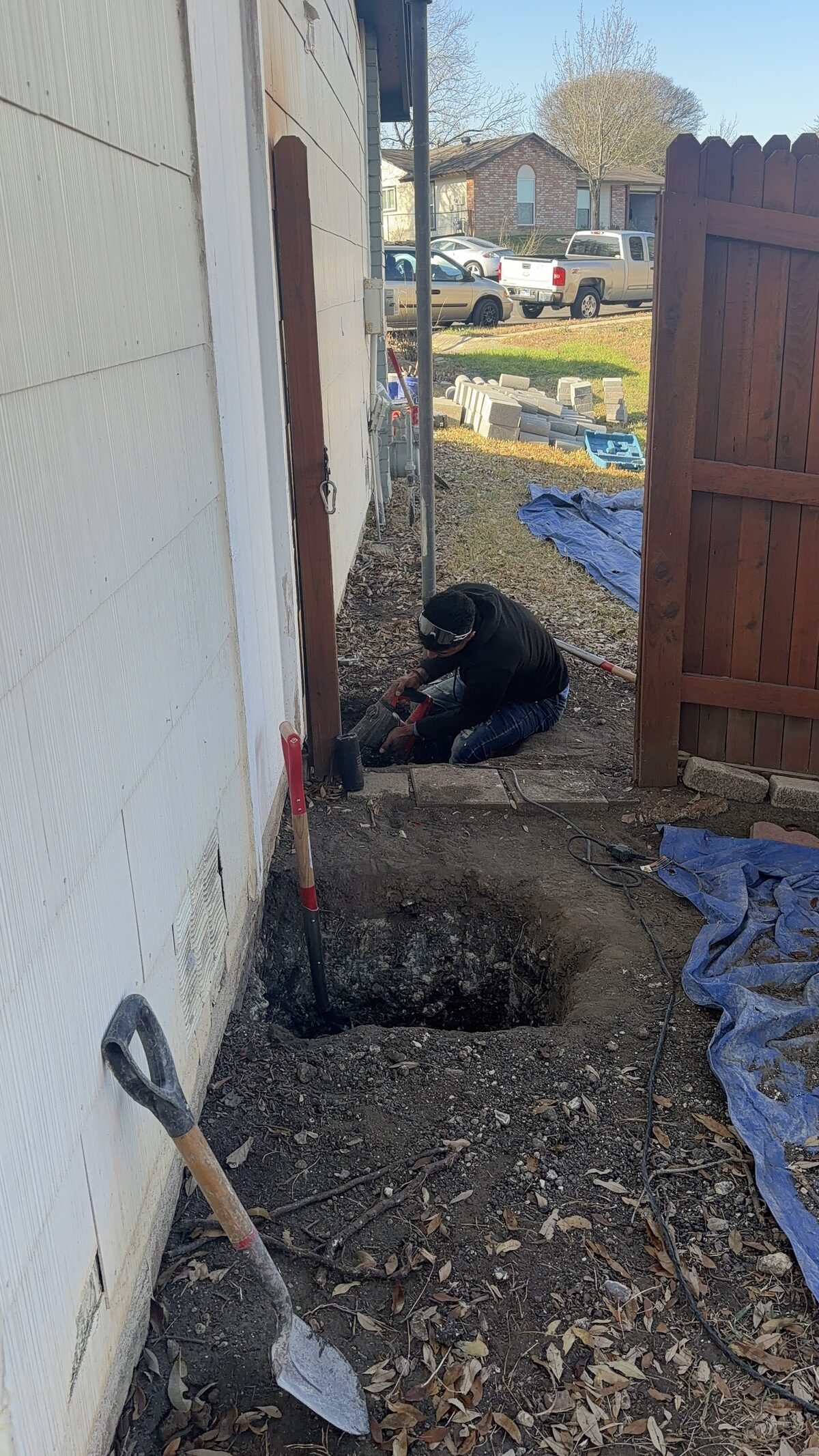 A crew hand-digging a pier pit for a foundation repair