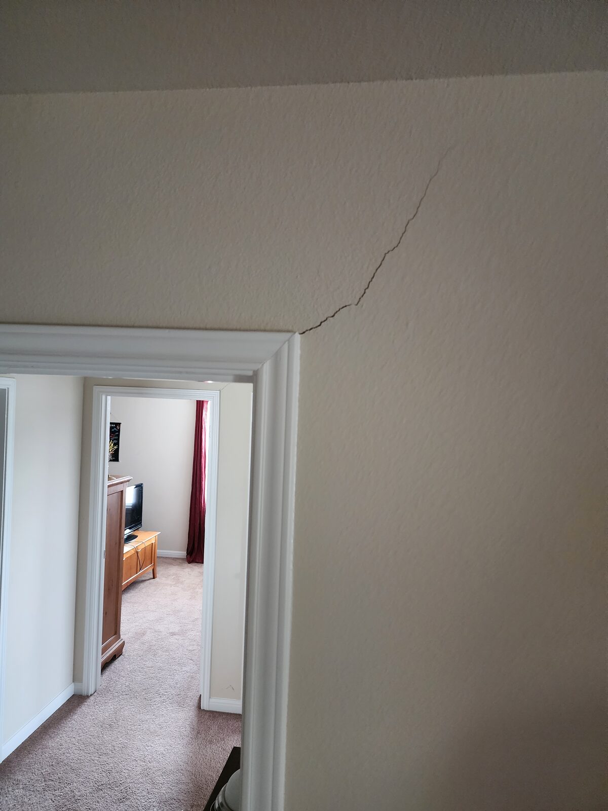 Diagonal crack rising from the corner of an interior doorway, often caused by foundation movement
