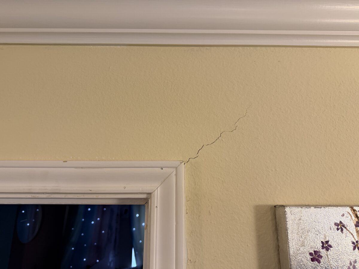 Diagonal crack climbing from window trim toward the ceiling, typical of foundation movement