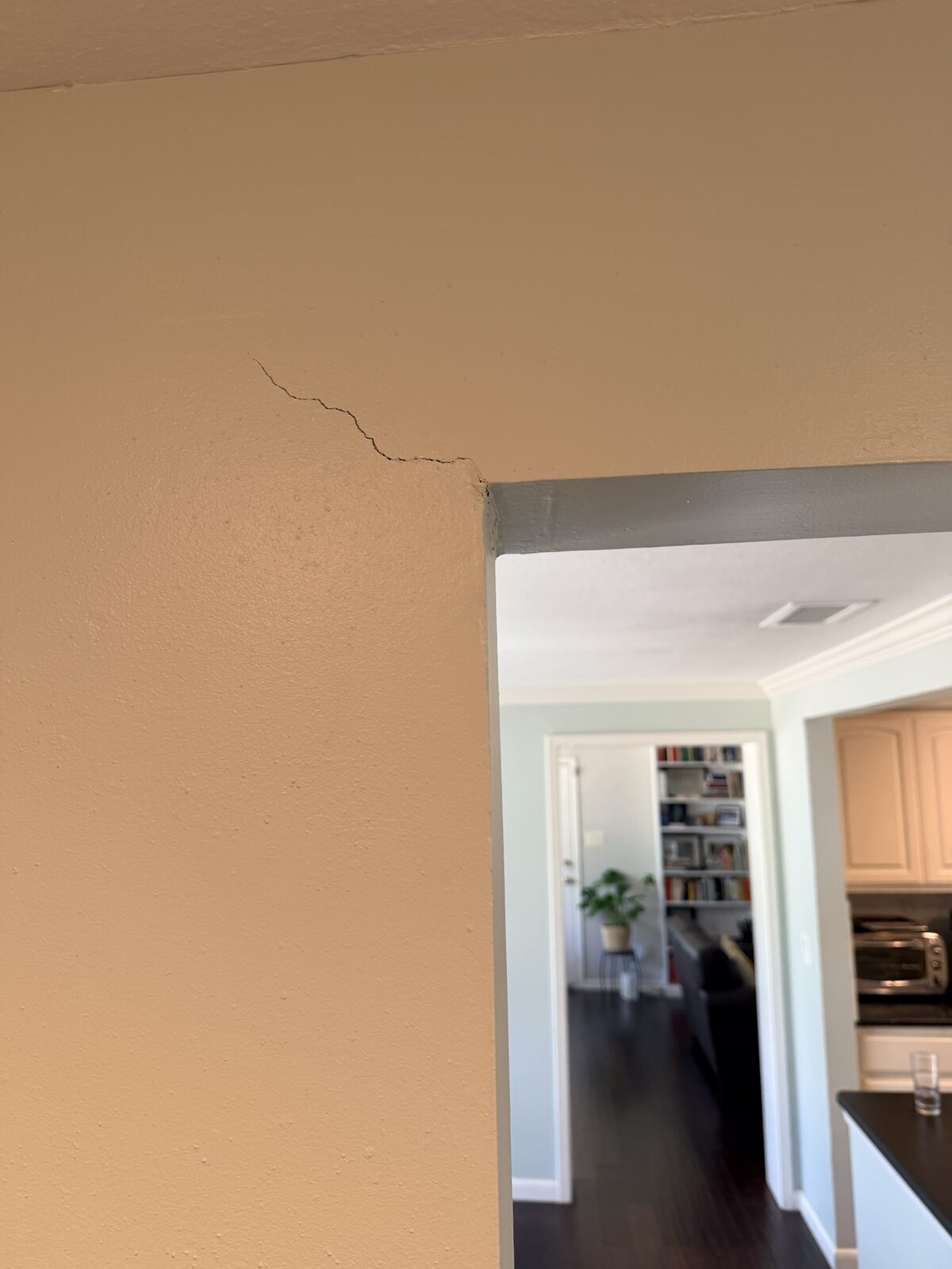 Diagonal drywall crack spreading from a doorway corner, typical evidence of foundation movement