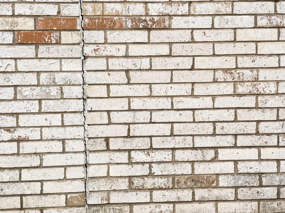 Diagonal settlement crack stepping through brick courses on an exterior wall