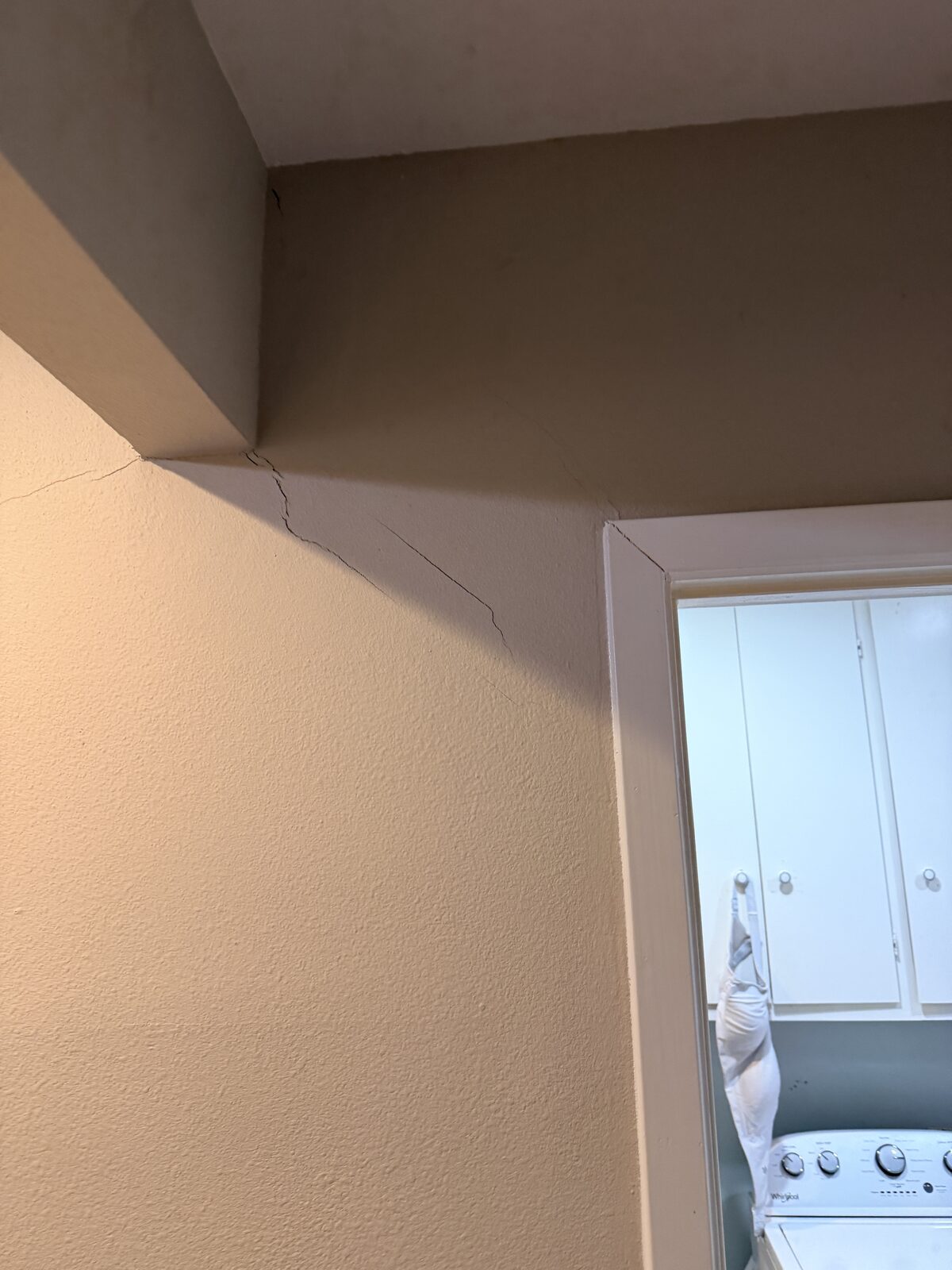 Drywall crack at a corner above the laundry room doorway, a sign of foundation settlement