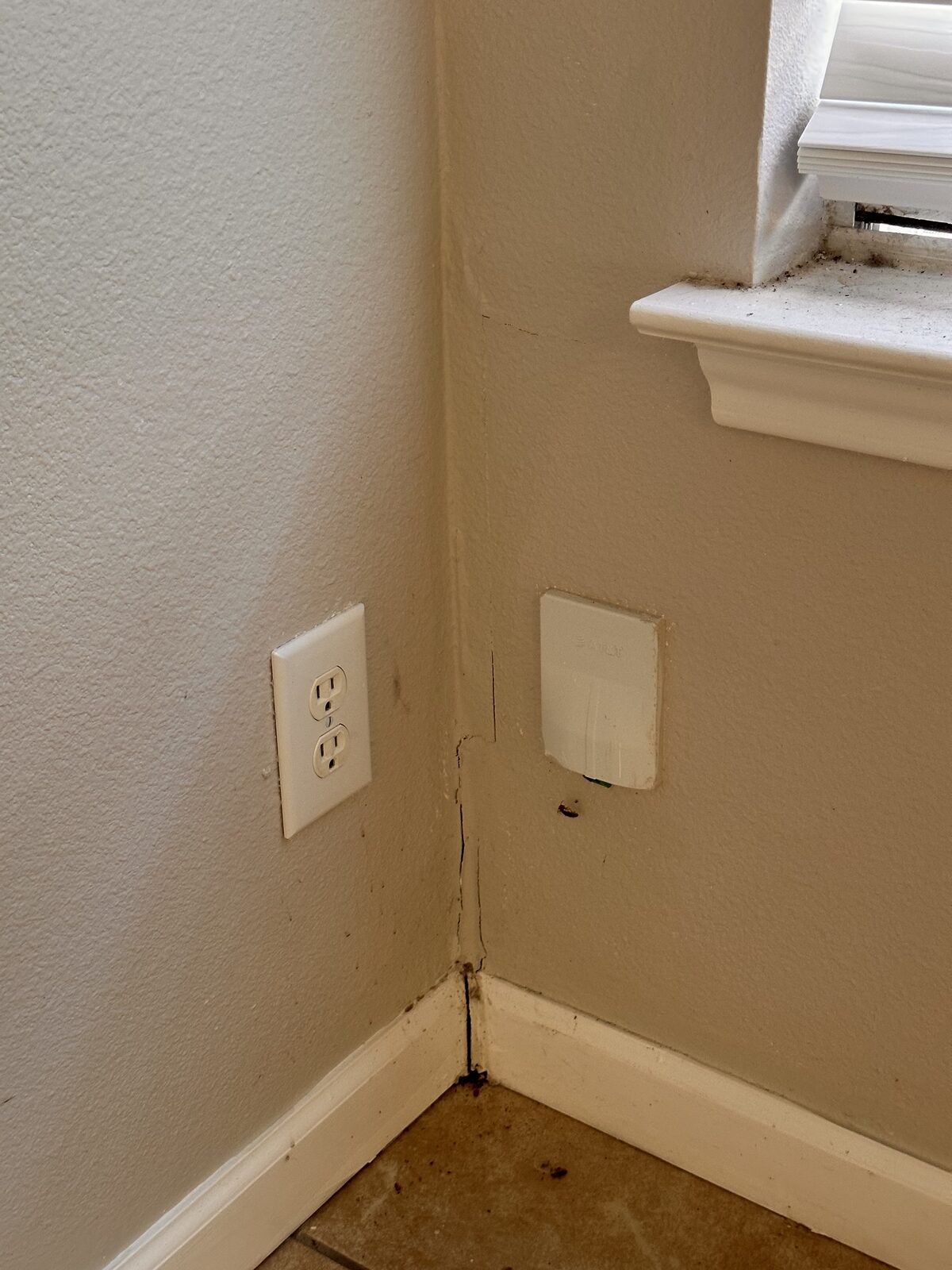 Drywall crack near a window and wall corner above an outlet, documented during a foundation inspection