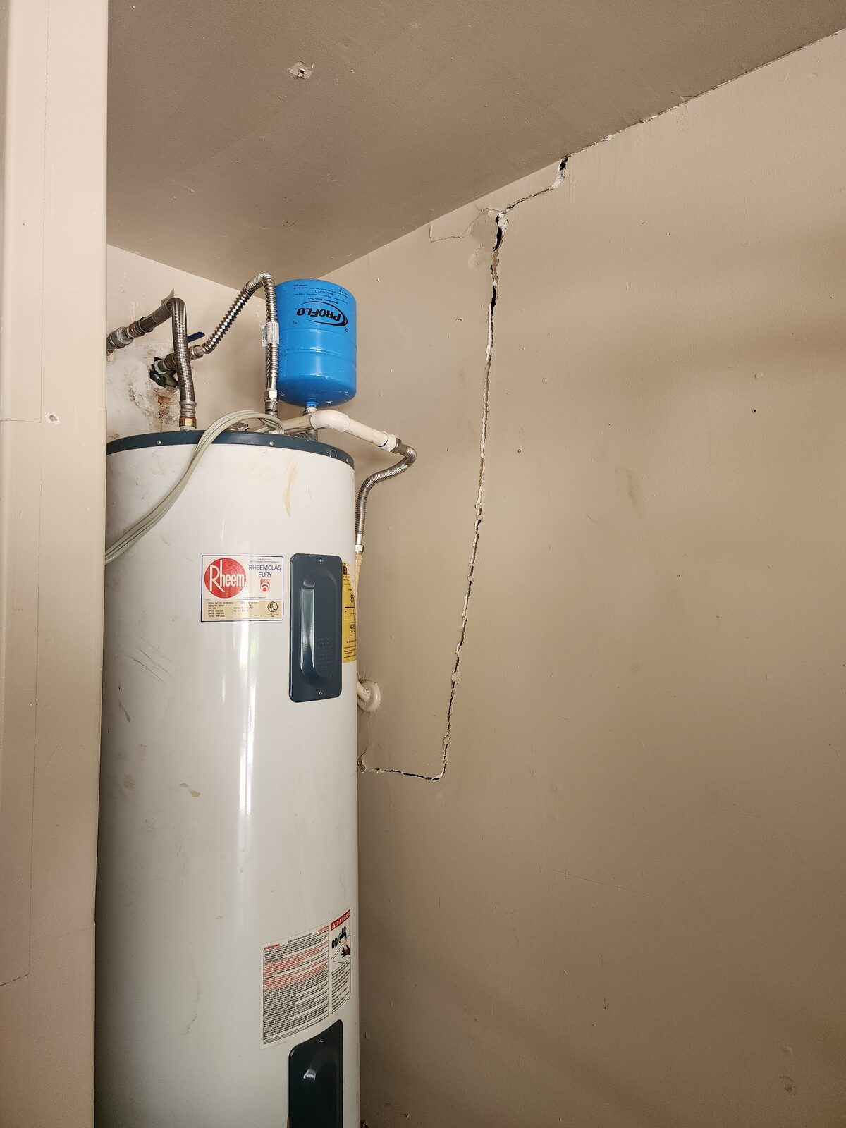 Zigzag drywall crack next to a water heater in a utility closet, documented during a foundation inspection