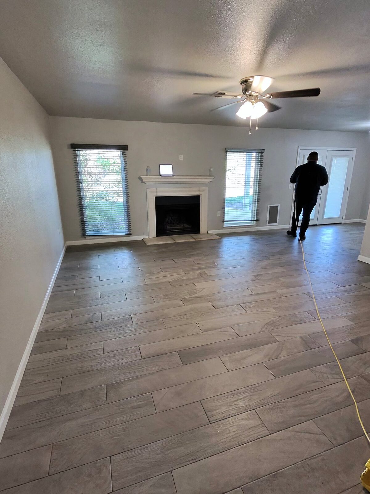 Empty living room with a yellow ZipLevel hose laid across the floor