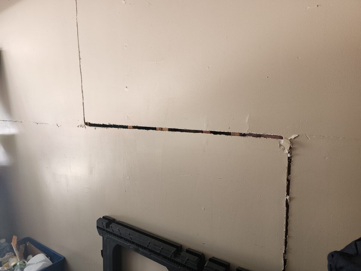 Drywall seam cracks with failed joint tape outlining a garage wall panel, an interior symptom of foundation settlement