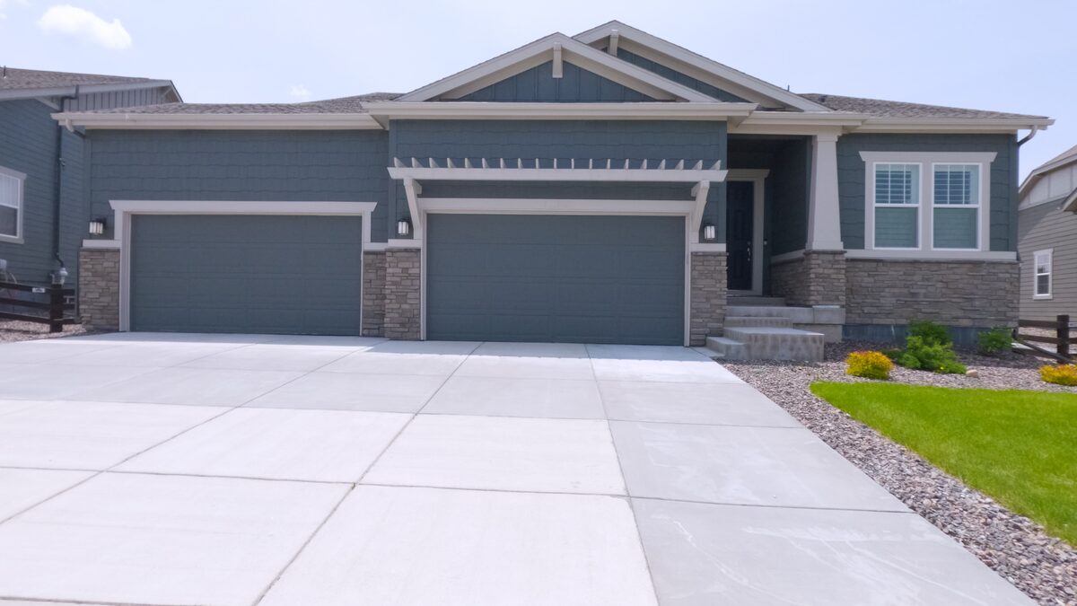 Finished wide concrete driveway with clean control joints leading to a three-car garage on a Central Texas home