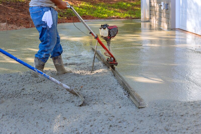 Worker power-screeding a freshly poured concrete slab
