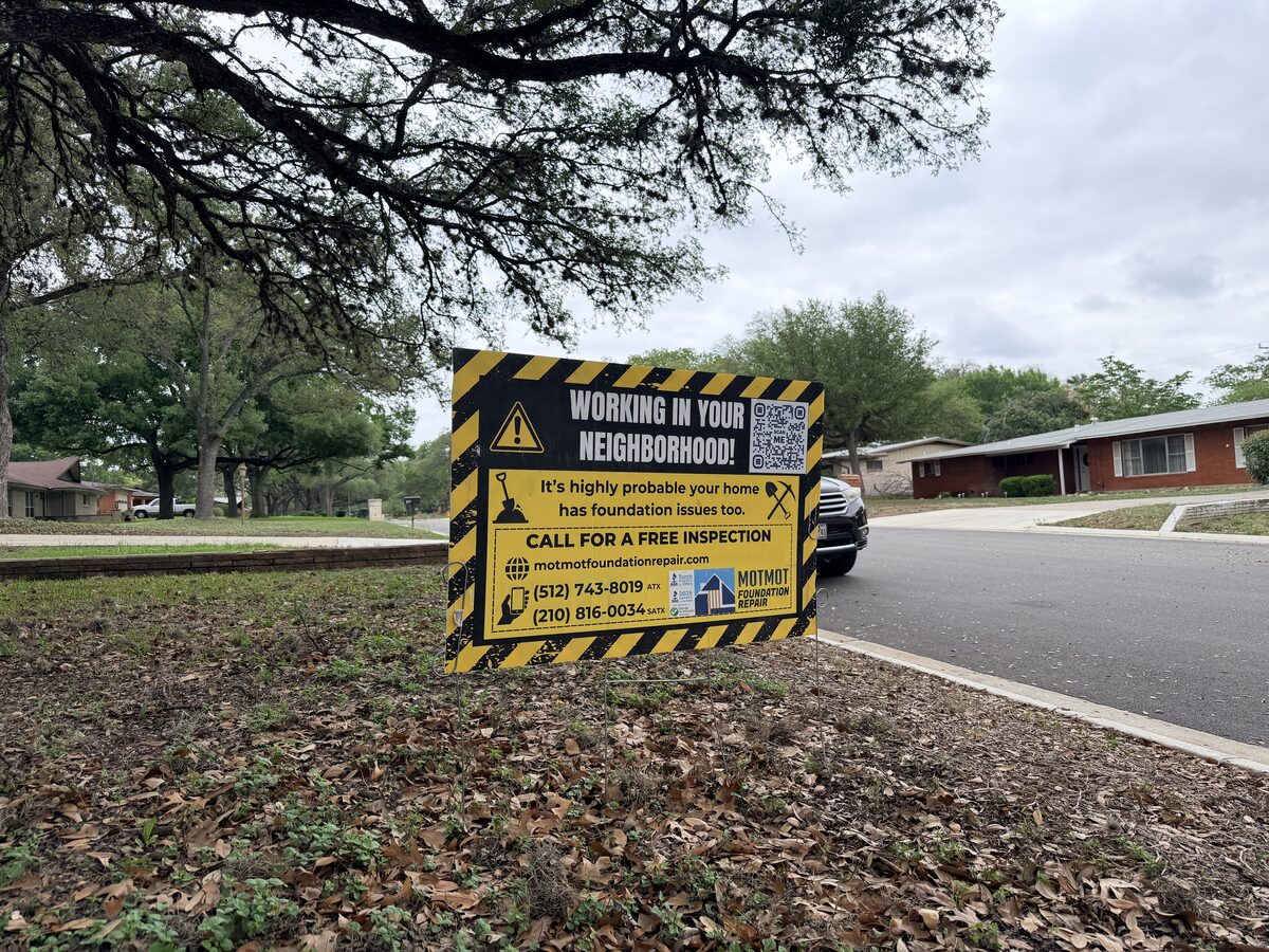 Working in Your Neighborhood yard sign for a foundation repair crew beside a residential street