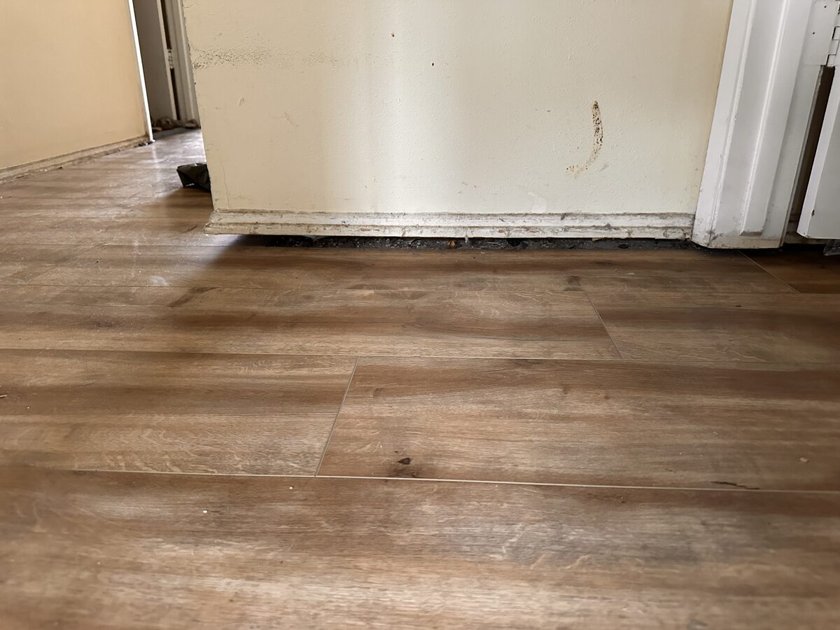 Gap visible beneath an interior wall along a plank floor, a classic sign a house needs leveling