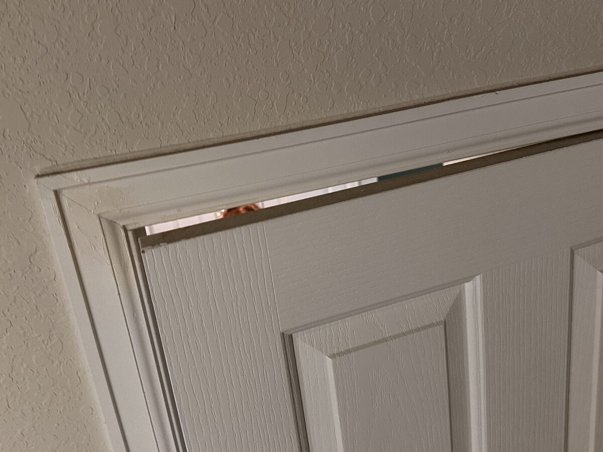 Uneven gap at the top corner of an interior door frame caused by foundation movement