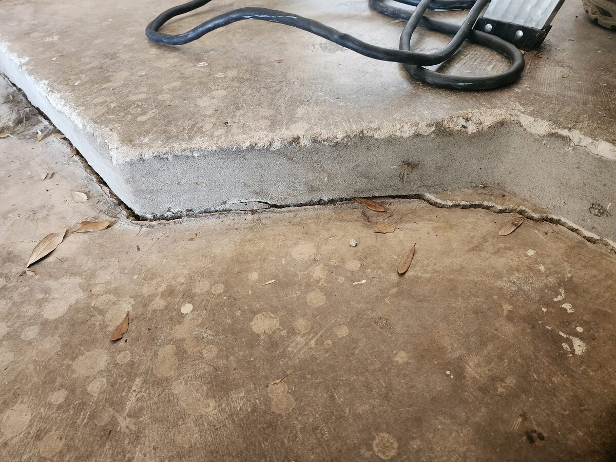 Settled garage slab showing a height offset and open gap along the joint, a sign of foundation movement