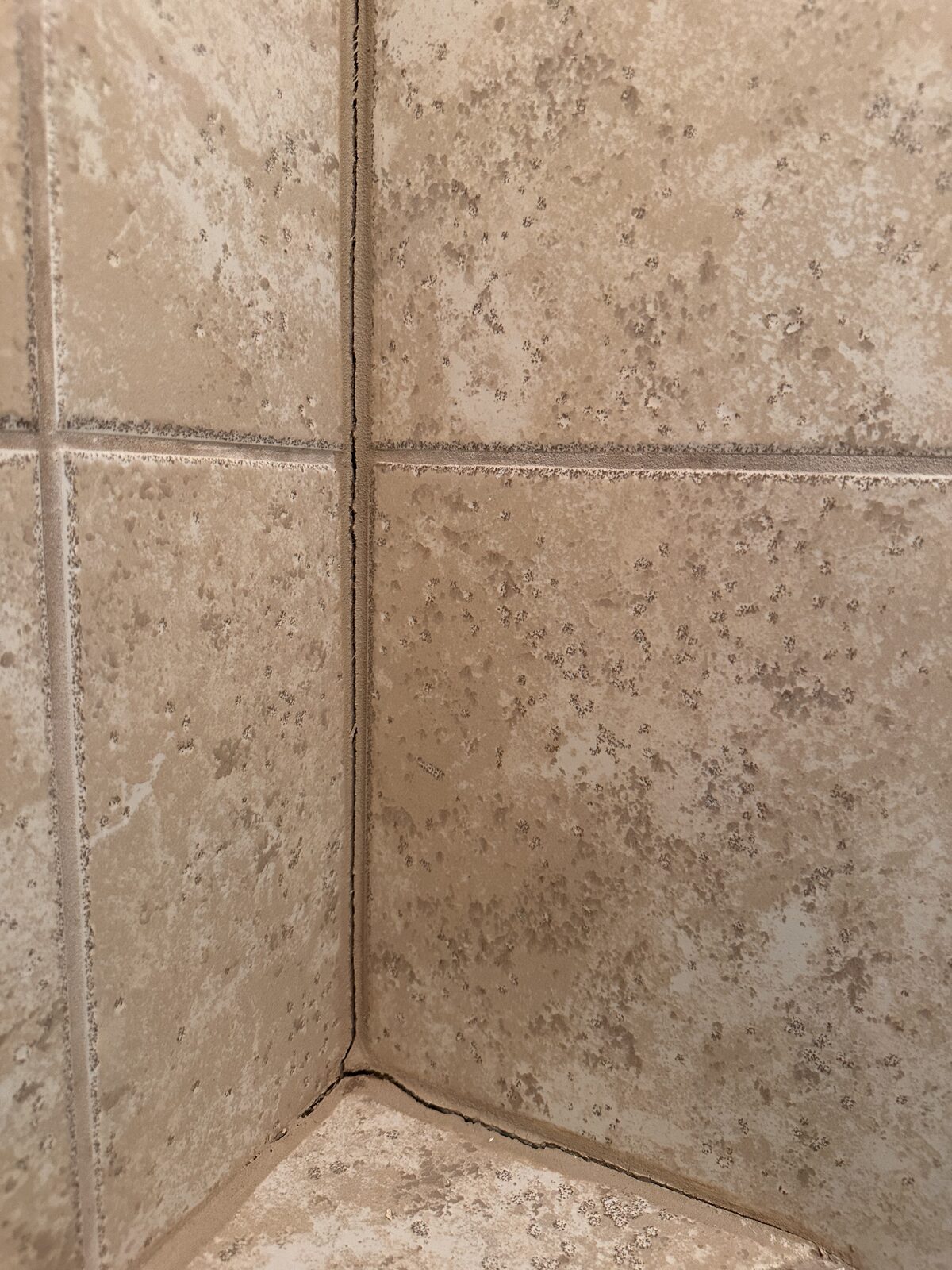 Grout separation running up a tiled shower corner caused by slab movement beneath the home