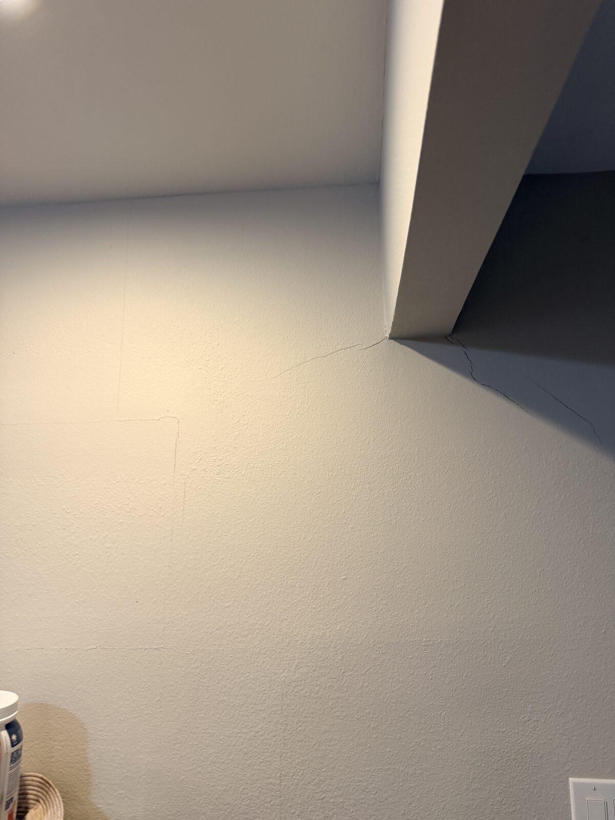 Hairline crack at the ceiling corner of an interior wall noted during a foundation inspection