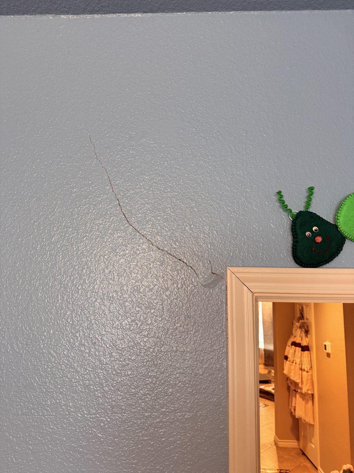 Hairline drywall crack above a bedroom door frame