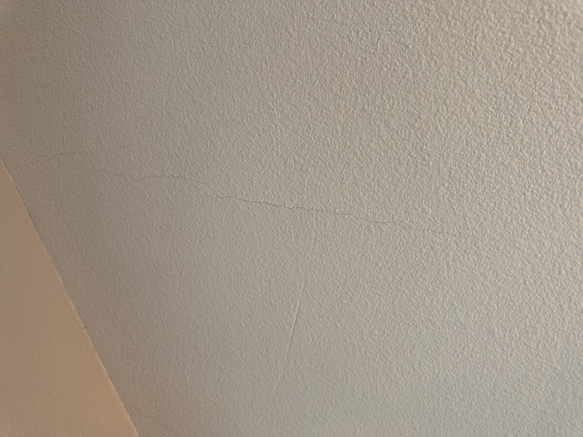 Hairline crack running across a textured ceiling, noted during a foundation inspection