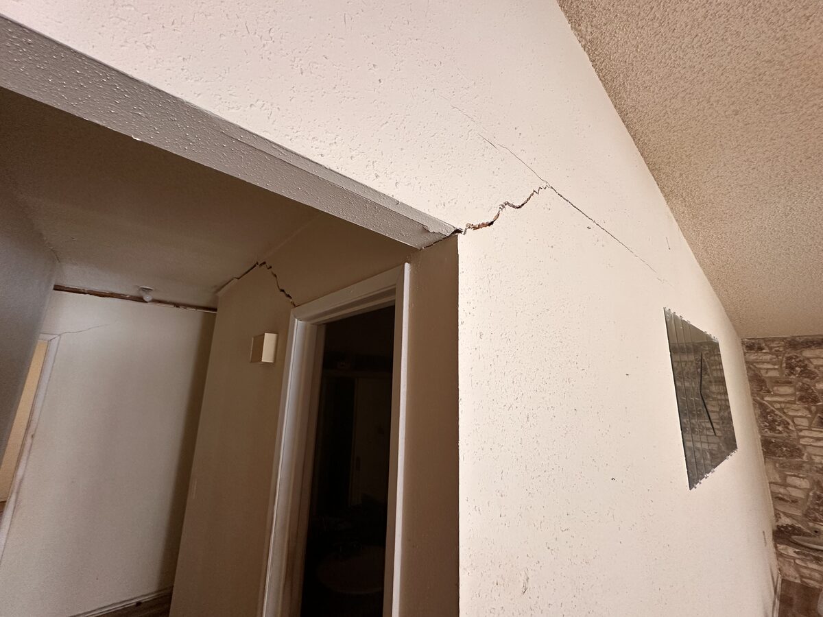 Hallway with settlement cracks running along the vaulted ceiling line above the door frames