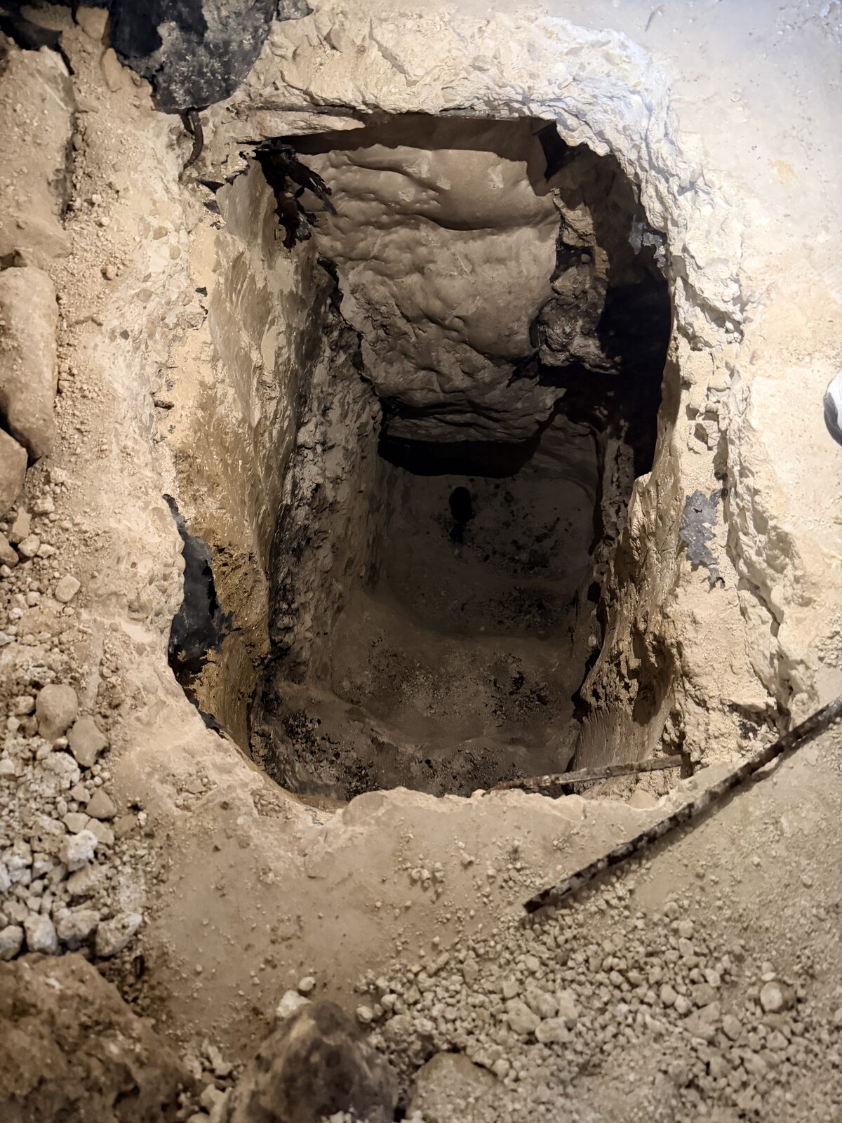 Hand-dug access pit and tunnel beneath a concrete slab foundation prepared for pier installation