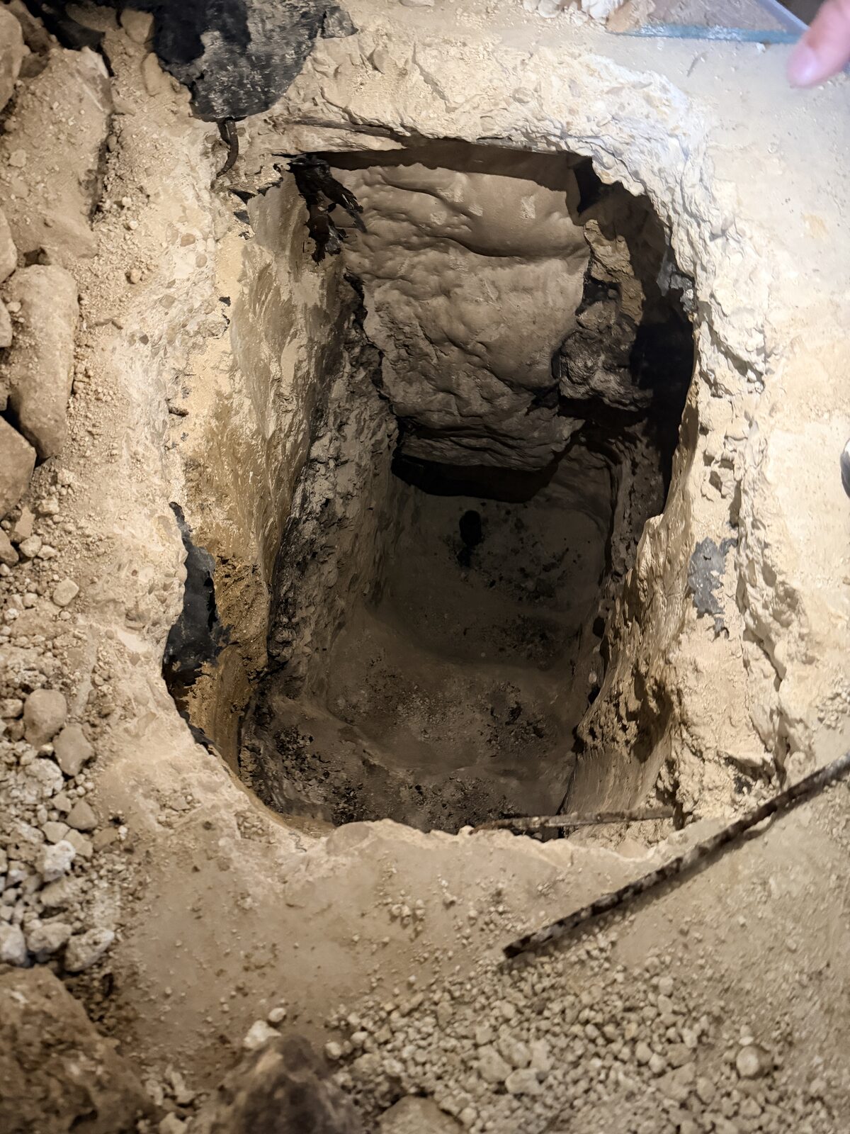 Hand-dug access pit exposing an interior grade beam for pier installation